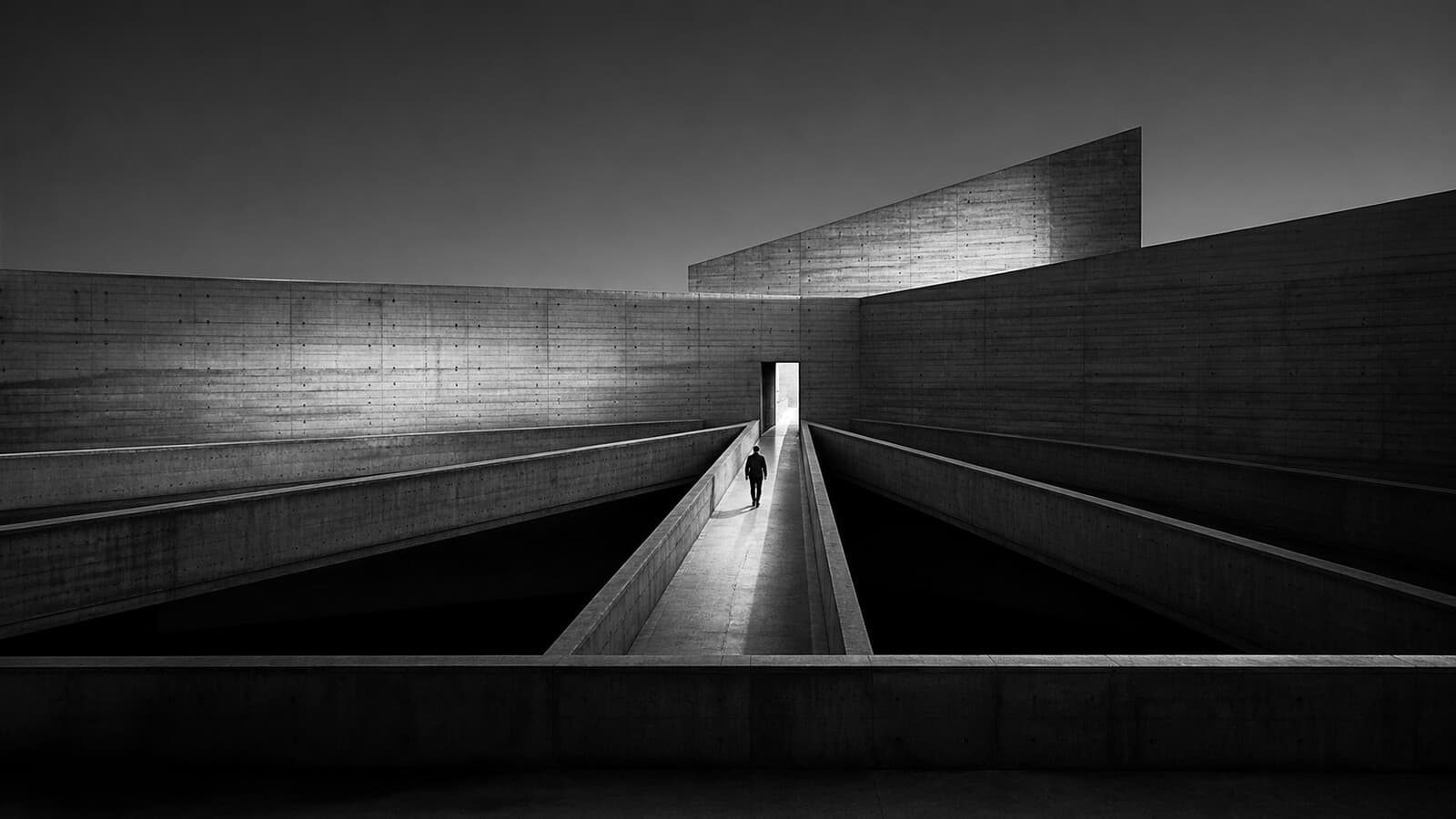 Concrete walkways converging toward a single lit doorway
