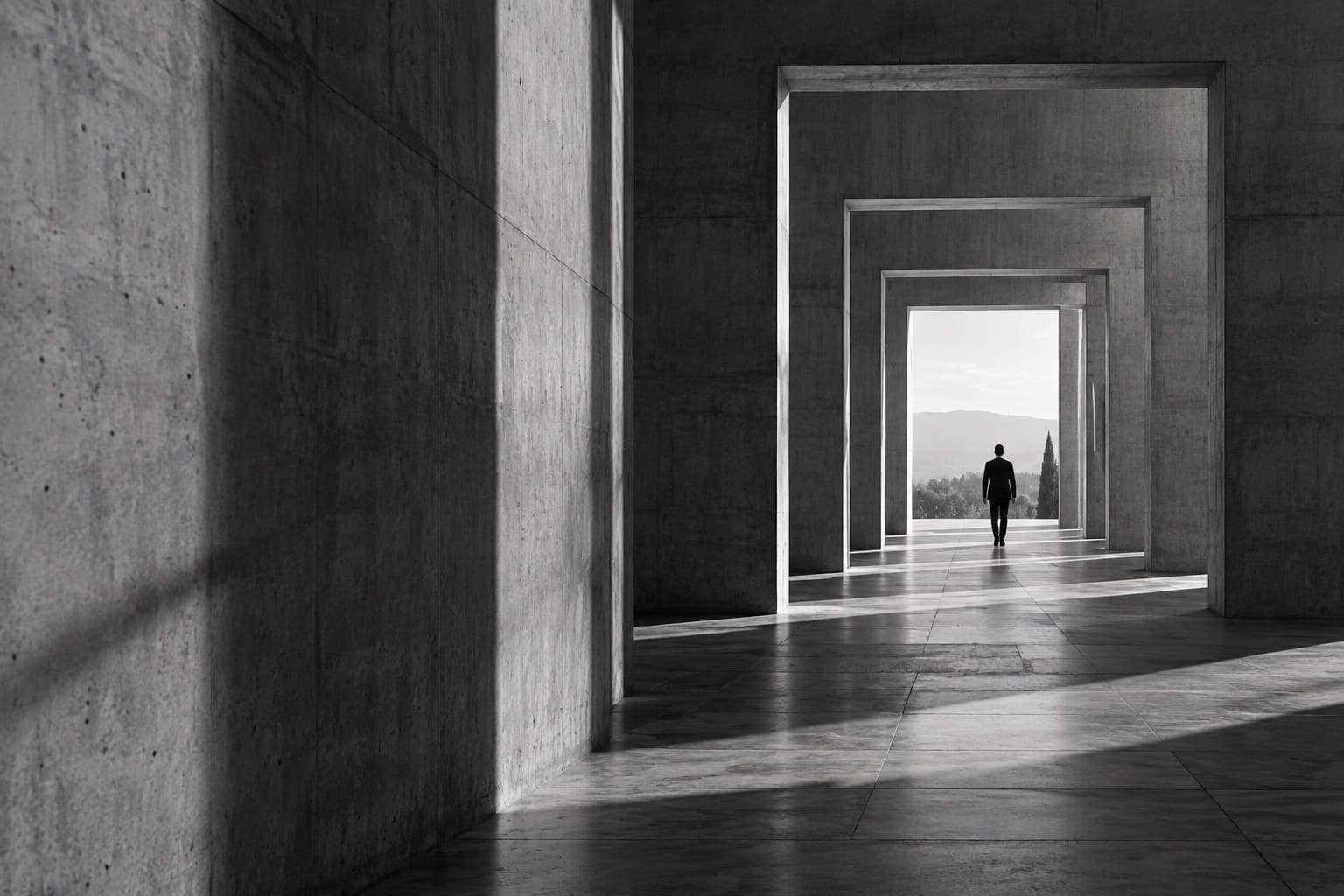 A lone figure walking through a sequence of monumental concrete doorways